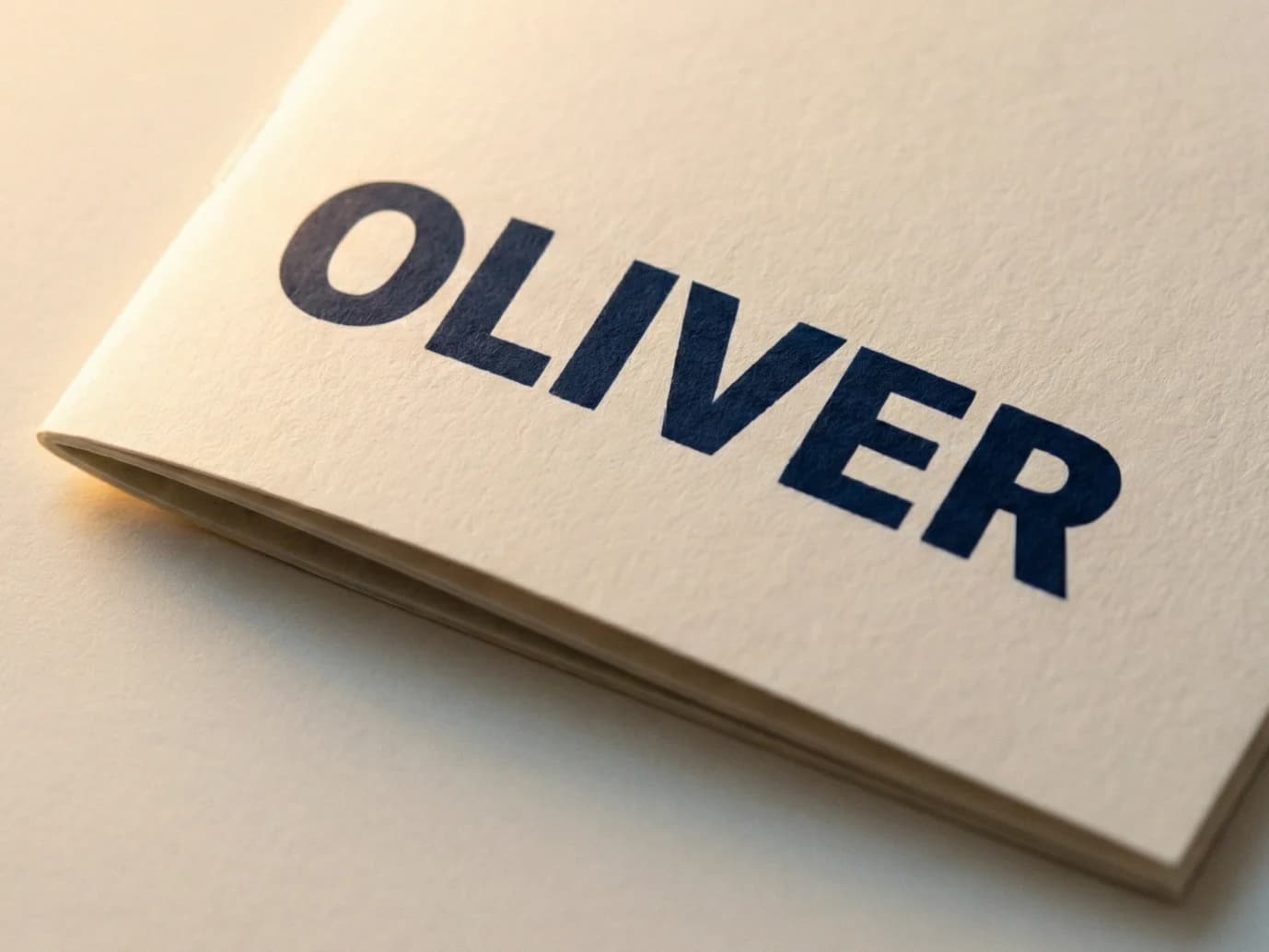Close-up of a toodaloo personalised colouring book cover showing the name OLIVER printed on premium off-white uncoated stock